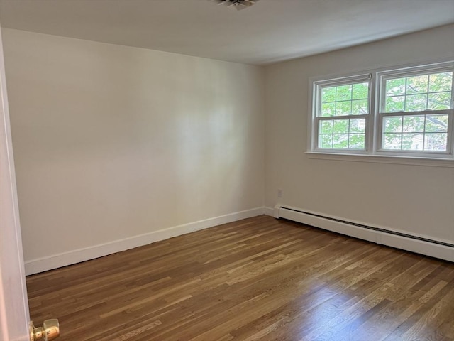 spare room featuring baseboard heating, wood finished floors, and baseboards