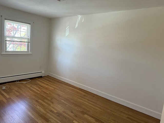 spare room featuring baseboards, wood finished floors, and baseboard heating