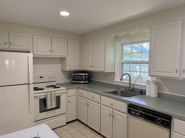 kitchen featuring white appliances, a sink, white cabinets, light tile patterned flooring, and decorative backsplash