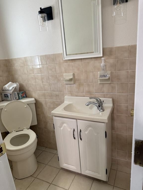 bathroom with tile walls, tile patterned flooring, vanity, toilet, and a wainscoted wall