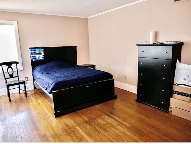 bedroom with wood-type flooring and ornamental molding