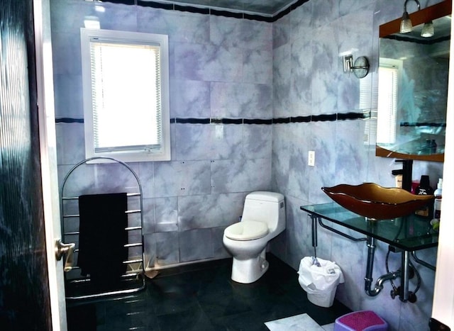 bathroom with tile patterned flooring, a wealth of natural light, tile walls, and sink