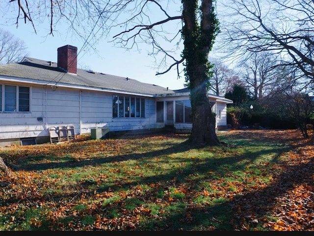 rear view of property featuring a lawn and a sunroom