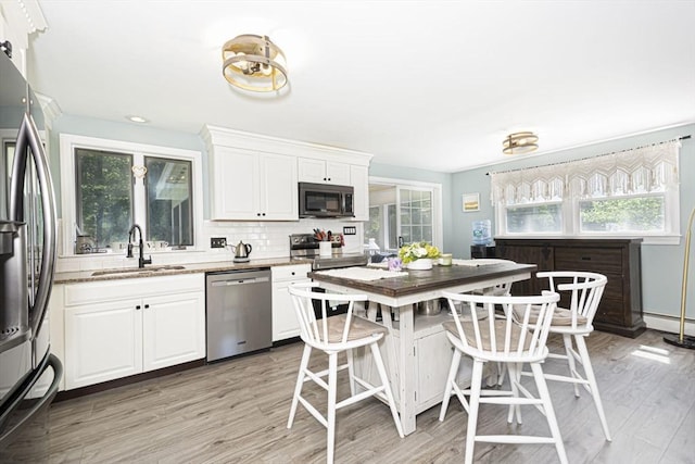 14 Robbins Rd, Ayer, MA 01432 - kitchen featuring stainless steel appliances, light wood-style flooring, white cabinets, decorative backsplash, and healthy amount of natural light