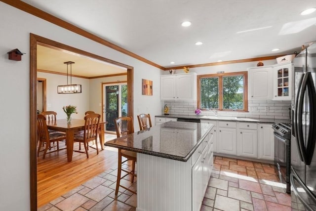 2 Lake Ave, Framingham, MA 01702 - kitchen with ornamental molding, stone tile flooring, freestanding refrigerator, tasteful backsplash, and white cabinetry