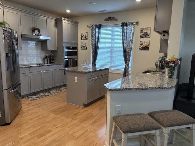 12101 Peters Farm Way Unit 12101, Westborough, MA 01581 - kitchen with appliances with stainless steel finishes, gray cabinetry, light wood finished floors, under cabinet range hood, and light stone countertops