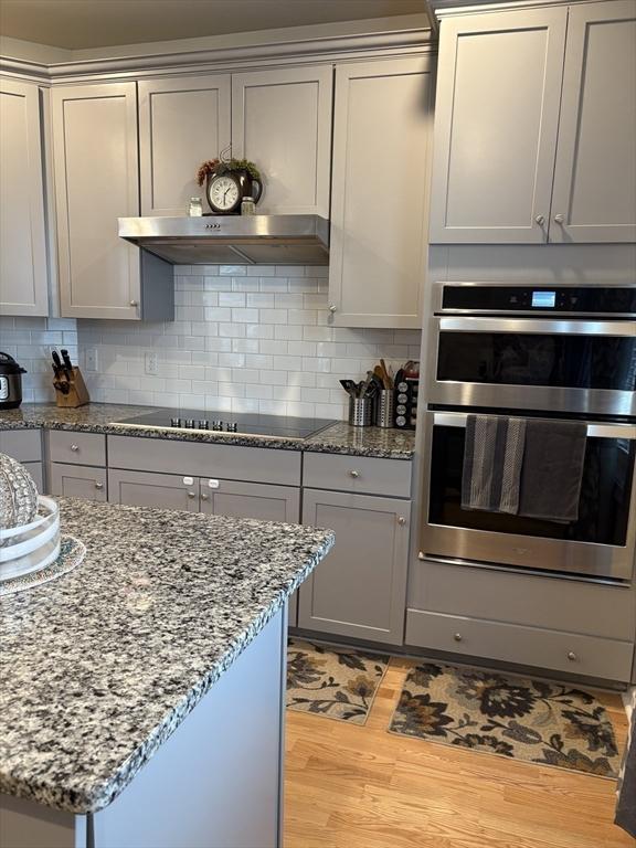 12101 Peters Farm Way Unit 12101, Westborough, MA 01581 - kitchen featuring double oven, black electric cooktop, gray cabinetry, light wood finished floors, and under cabinet range hood