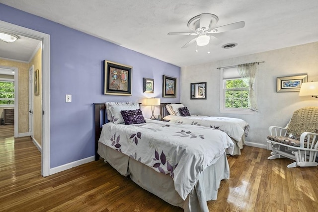 bedroom featuring baseboards, multiple windows, and wood finished floors