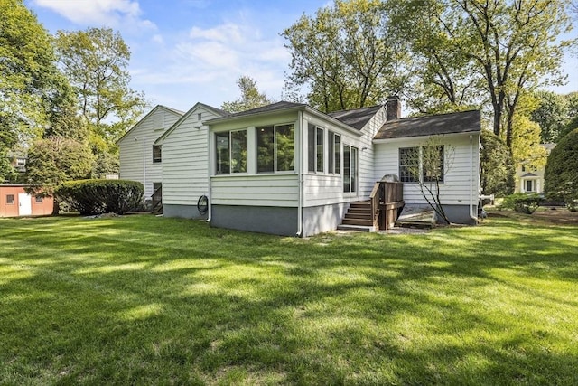 back of property featuring a chimney, a sunroom, and a yard