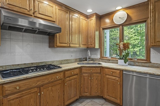 kitchen with appliances with stainless steel finishes, a sink, under cabinet range hood, brown cabinetry, and recessed lighting