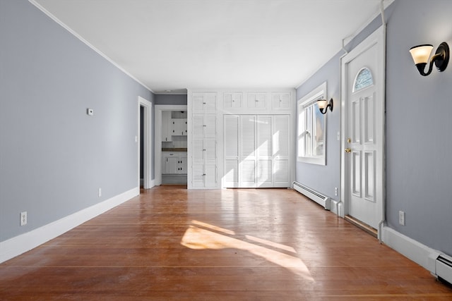 interior space with crown molding, wood-type flooring, and baseboard heating