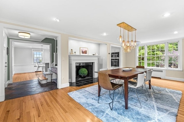 4 Worthen Rd, Winchester, MA 01890 - dining room with a chandelier, radiator heating unit, light wood-style floors, ornamental molding, and a tile fireplace