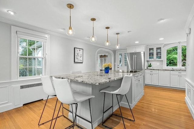 4 Worthen Rd, Winchester, MA 01890 - kitchen featuring radiator, stainless steel refrigerator, ornamental molding, white cabinetry, and light wood-style floors