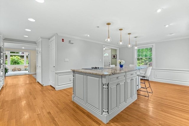 4 Worthen Rd, Winchester, MA 01890 - kitchen with crown molding, a center island, black electric stovetop, a kitchen breakfast bar, and light wood-style flooring