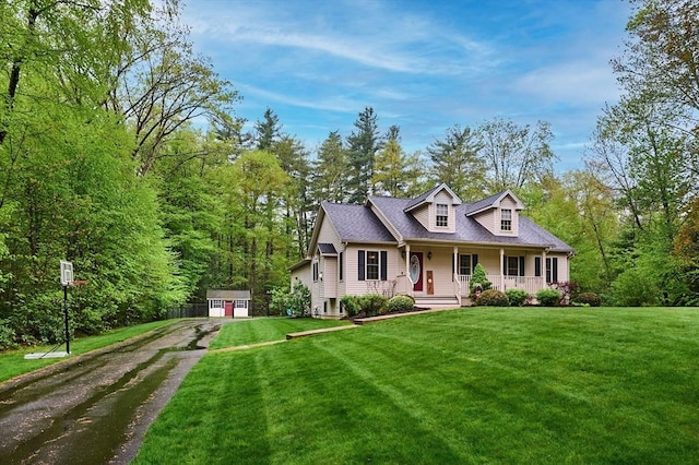 cape cod house with a porch, a front lawn, a shed, and an outdoor structure