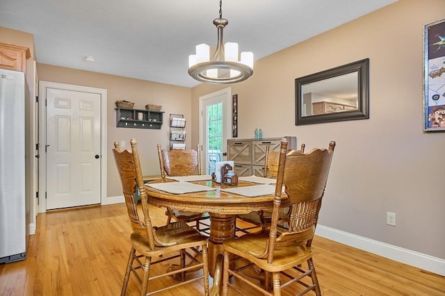 dining area with light wood-style flooring, baseboards, and a chandelier