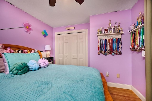 bedroom with wood finished floors, a closet, baseboards, and ceiling fan