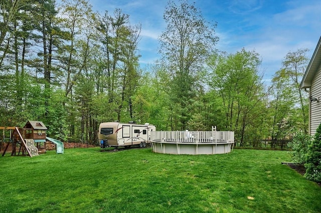 view of green lawn featuring an outdoor pool and a playground