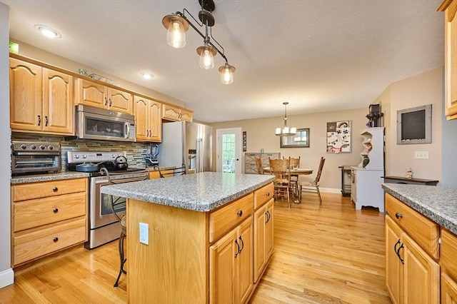 kitchen featuring appliances with stainless steel finishes, light wood-style floors, a center island, a chandelier, and recessed lighting