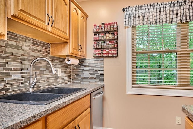 kitchen featuring a sink, backsplash, stainless steel dishwasher, and light countertops