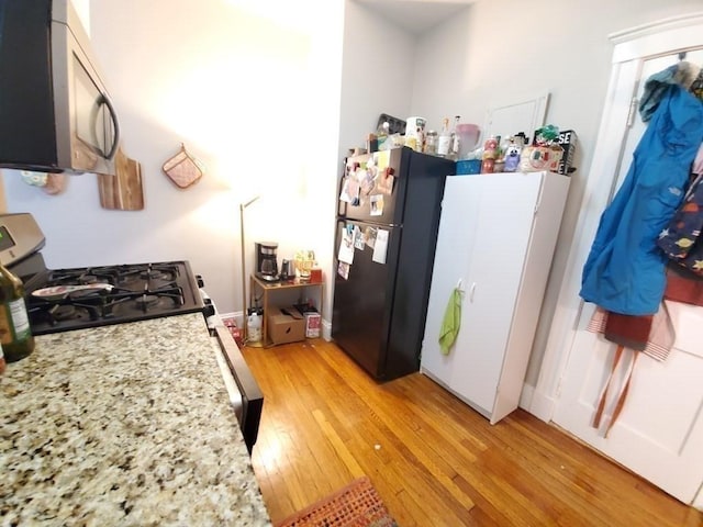 kitchen with light stone counters, light wood finished floors, and stainless steel appliances