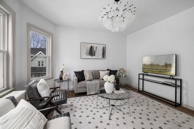 living area featuring a notable chandelier, baseboards, and wood finished floors