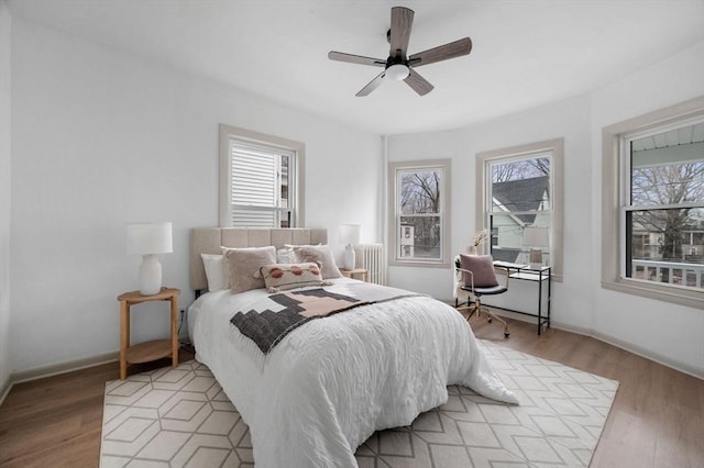 bedroom featuring multiple windows, light wood-style flooring, and radiator heating unit