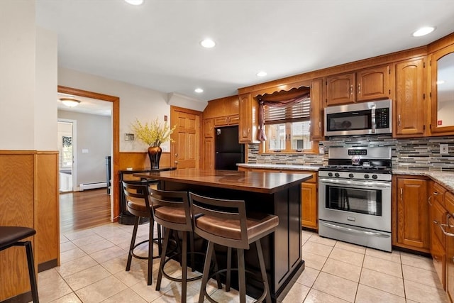 7 Coolidge Rd, Danvers, MA 01923 - kitchen with stainless steel appliances, a baseboard radiator, plenty of natural light, a wainscoted wall, and a breakfast bar