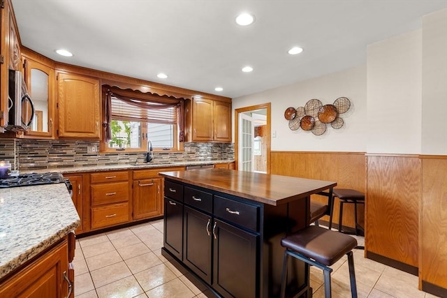7 Coolidge Rd, Danvers, MA 01923 - kitchen with stainless steel microwave, a sink, a kitchen bar, wainscoting, and brown cabinets