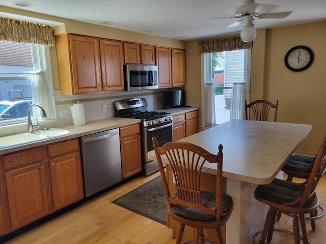 40 June St, Worcester, MA 01602 - kitchen featuring appliances with stainless steel finishes, light wood-type flooring, brown cabinetry, and backsplash