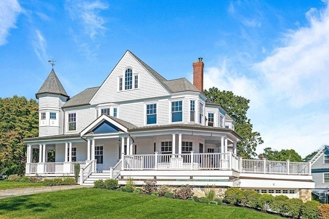 victorian home with covered porch, a chimney, and a front lawn