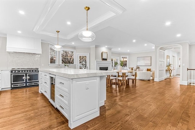 kitchen with range with two ovens, white cabinetry, light countertops, a center island, and decorative light fixtures