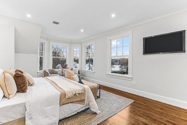 bedroom with visible vents, crown molding, baseboards, and wood finished floors