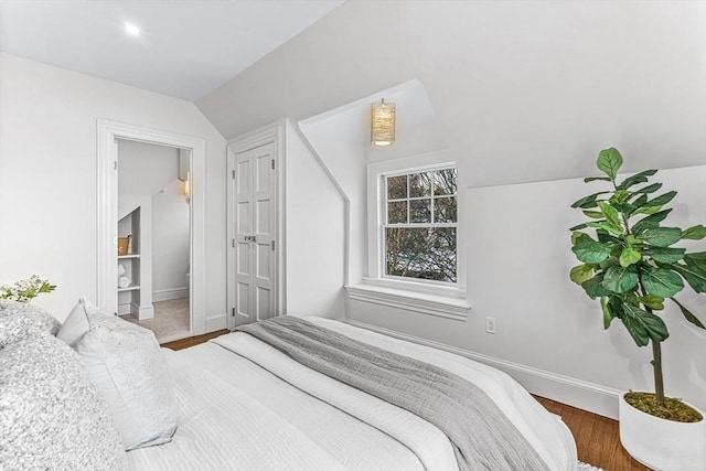 bedroom featuring lofted ceiling, wood finished floors, and baseboards