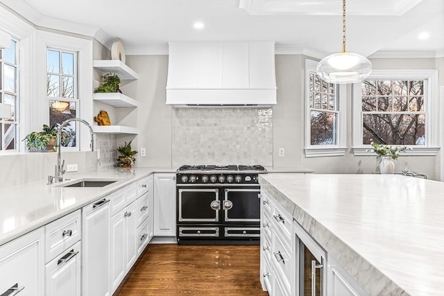 kitchen featuring beverage cooler, white cabinets, custom range hood, pendant lighting, and a sink