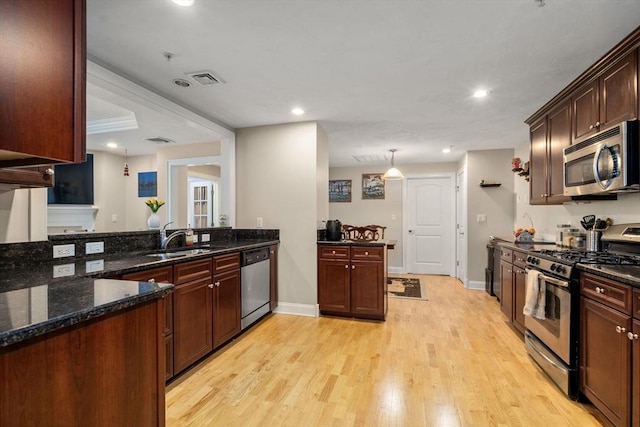 kitchen with sink, light hardwood / wood-style flooring, hanging light fixtures, dark stone counters, and stainless steel appliances