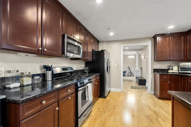 kitchen featuring appliances with stainless steel finishes, light wood-type flooring, and dark stone counters