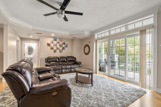 living room featuring crown molding, ceiling fan, a raised ceiling, and light hardwood / wood-style floors