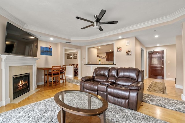 living room with crown molding, ceiling fan, and light wood-type flooring