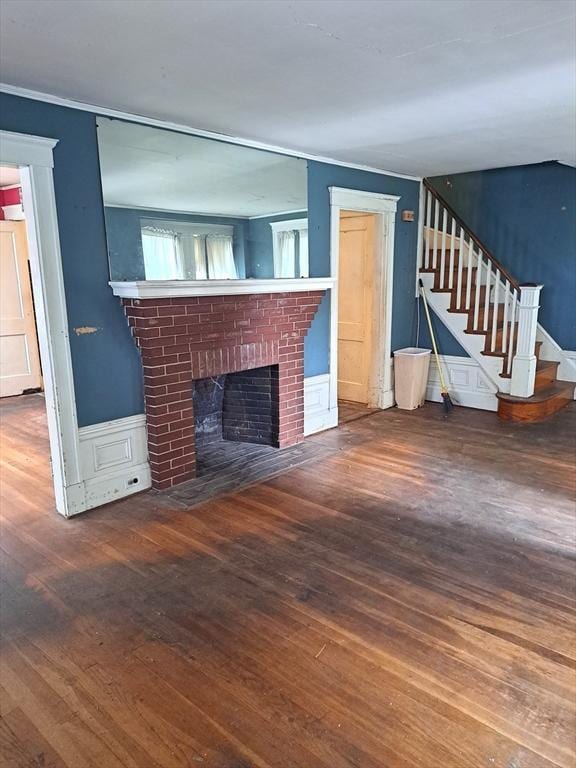 281 Elmwood Ave, Quincy, MA 02170 - unfurnished living room featuring wood finished floors, a brick fireplace, stairs, crown molding, and wainscoting