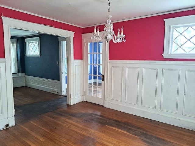 281 Elmwood Ave, Quincy, MA 02170 - unfurnished dining area featuring a chandelier, a wainscoted wall, dark wood-type flooring, crown molding, and a decorative wall