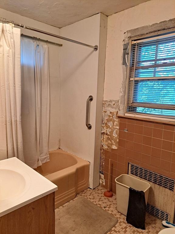281 Elmwood Ave, Quincy, MA 02170 - full bath featuring radiator heating unit, tile walls, vanity, shower / bathtub combination with curtain, and wainscoting