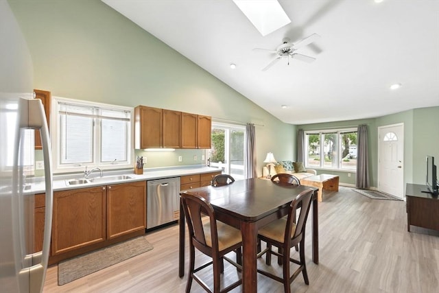 kitchen with a sink, stainless steel dishwasher, a skylight, light wood-style floors, and brown cabinets