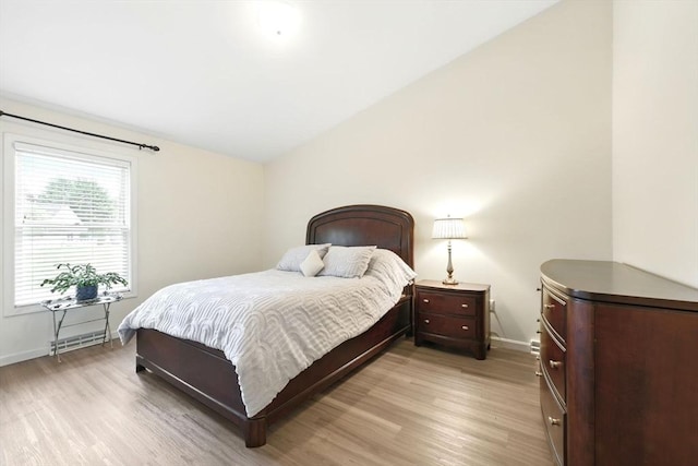 bedroom with light wood-type flooring, baseboards, and lofted ceiling