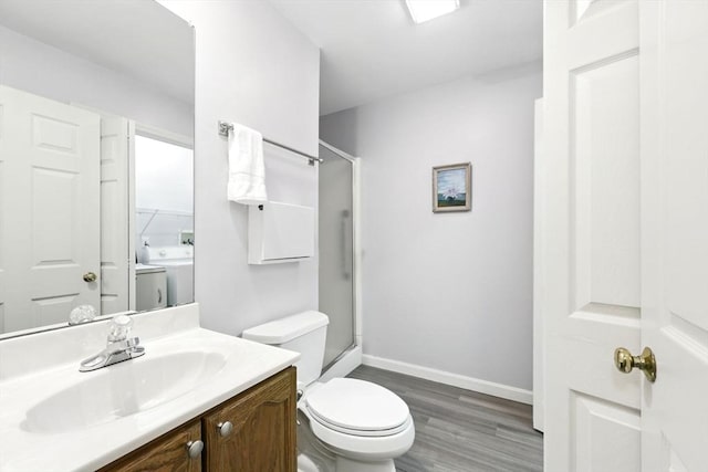 full bathroom with washer and clothes dryer, wood finished floors, toilet, baseboards, and a shower with shower door