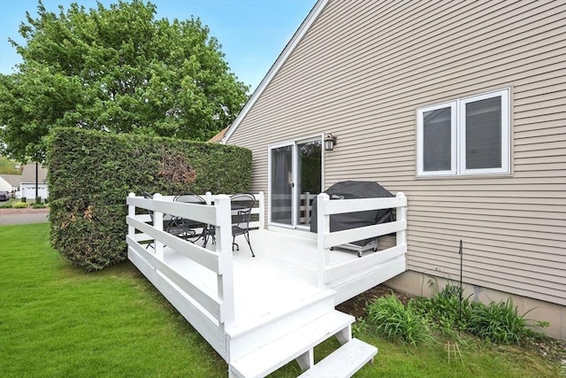 wooden deck featuring a lawn and outdoor dining area