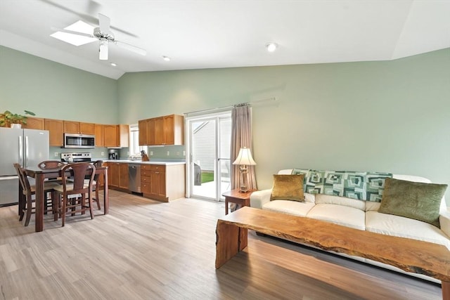 living room with high vaulted ceiling, a ceiling fan, and light wood-type flooring