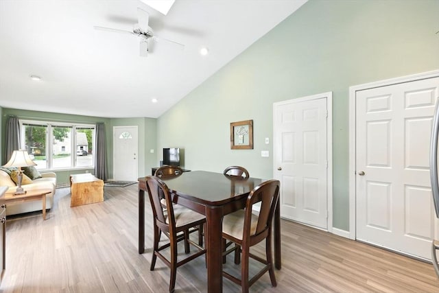 dining room with light wood-style floors, ceiling fan, high vaulted ceiling, and baseboards