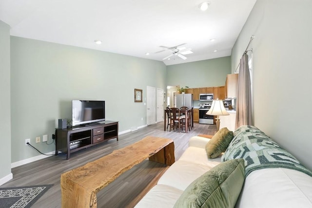 living room with baseboards, light wood-type flooring, a ceiling fan, recessed lighting, and high vaulted ceiling