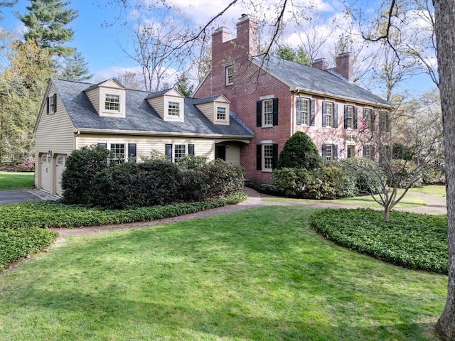 view of front of home featuring a garage, a front lawn, and a chimney